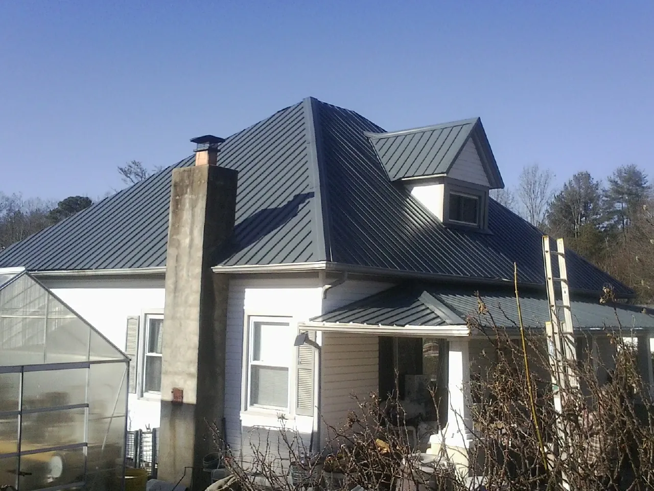 Dark blue standing seam metal roof on a white farmhouse with dormer — Slate & Tile Roof Repair by Roofing Brothers in Thorntown