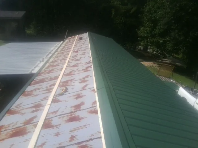Old rusted panels beside newly installed green metal roofing — Wind Damage Roof Repair by Roofing Brothers in Thorntown