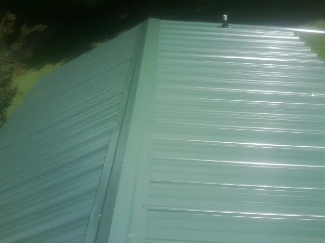 New green metal panels meeting at the ridge of a roof — Flat Roof Repair work by our crew in Thorntown