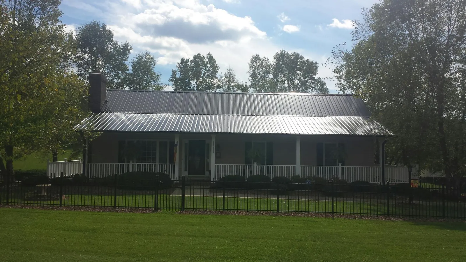 Gray metal roof on a brick ranch with a full width front porch — Gutter Guard Installation work by our crew in Thorntown